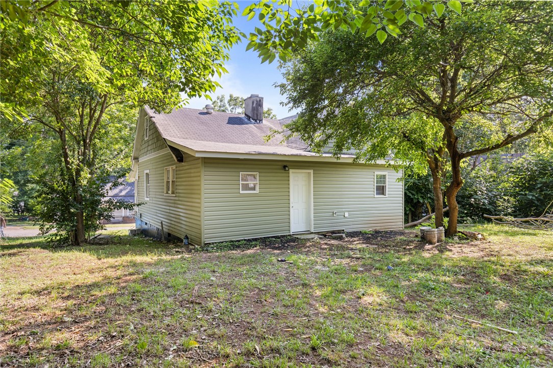 109 Farmer Street Anderson, SC 29621 - Photo 5 of 31 A modest home with inviting siding is framed by mature trees, offering tranquil outdoor living.