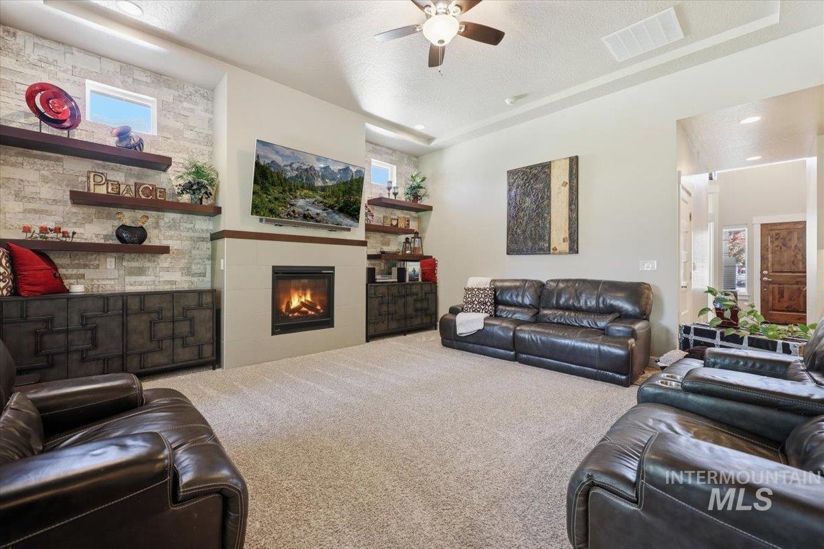 1303 West Brando Street Meridian, ID 83646 - Photo 19 of 49 Spacious living area featuring a central fireplace with an integrated media niche, recessed lighting, a ceiling fan, and built-in shelving
