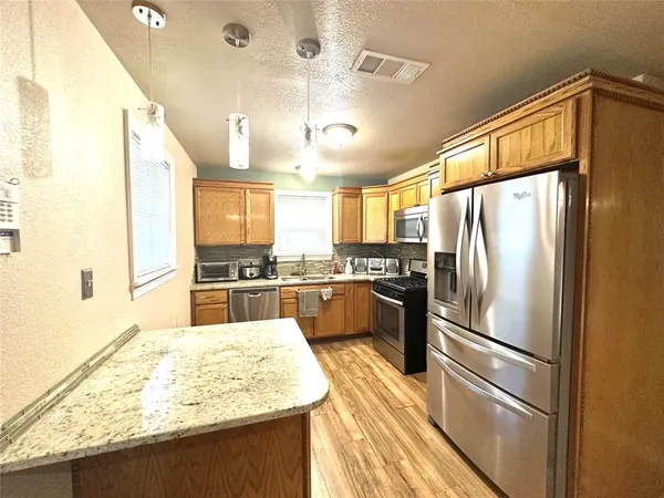 a kitchen with stainless steel appliances a refrigerator and wooden floor