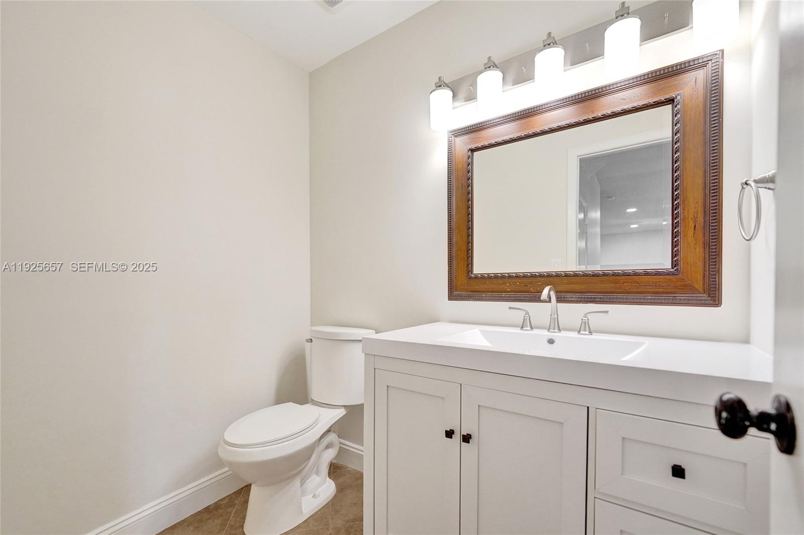9340 Southwest 61st Way, Unit B Boca Raton, FL 33428 - Photo 11 of 25 a bathroom with a toilet sink vanity and mirror