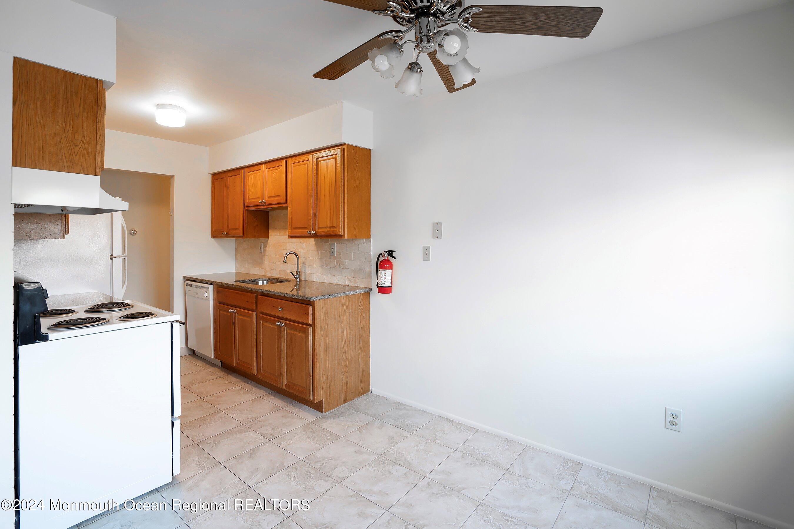 80 Manchester Court, Unit F Freehold, NJ 07728 - Photo 4 of 10 a kitchen with a stove a sink and a refrigerator