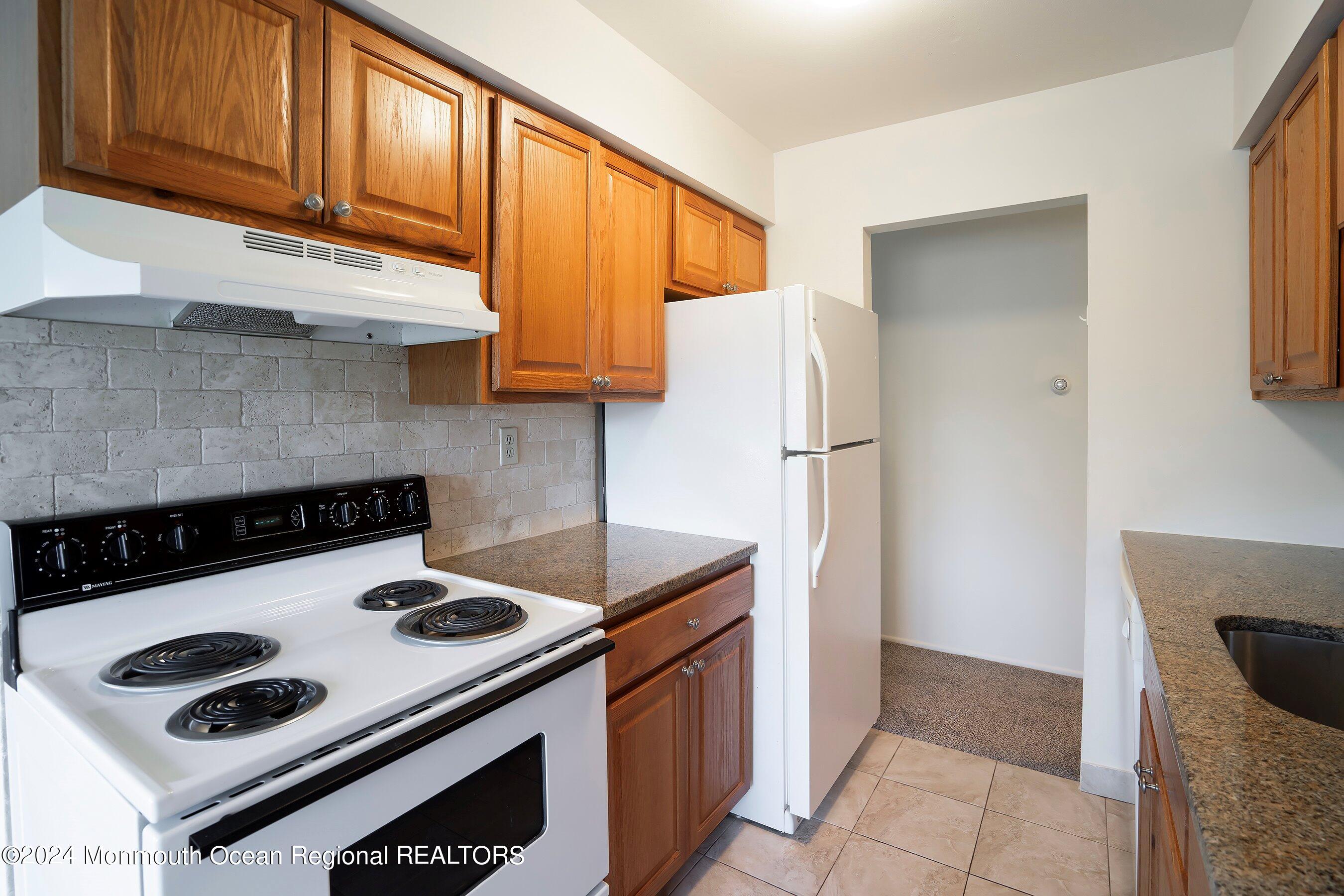 80 Manchester Court, Unit F Freehold, NJ 07728 - Photo 8 of 10 a kitchen with a stove a refrigerator and a sink