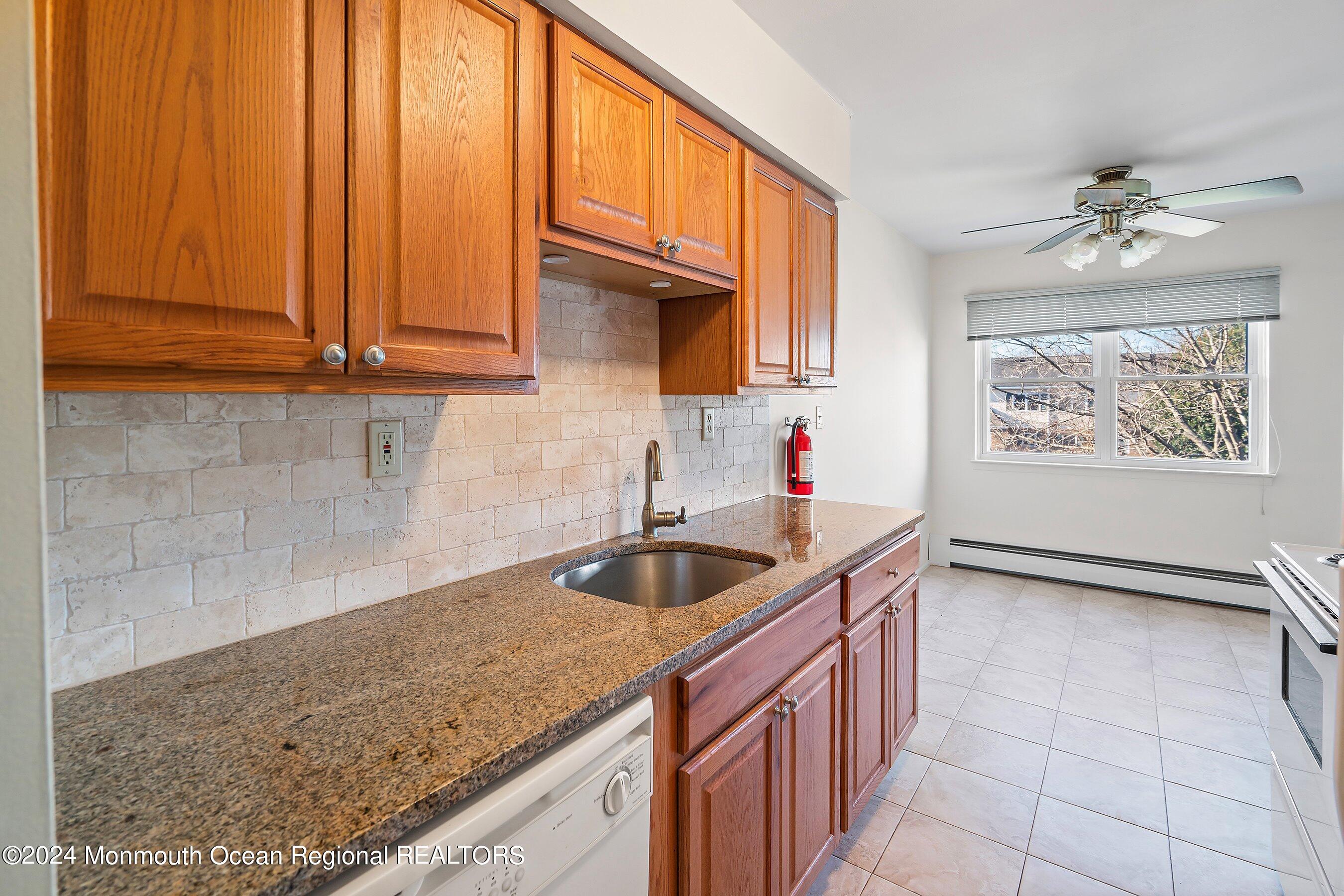80 Manchester Court, Unit F Freehold, NJ 07728 - Photo 9 of 10 a kitchen with granite countertop a sink stainless steel appliances cabinets and a window