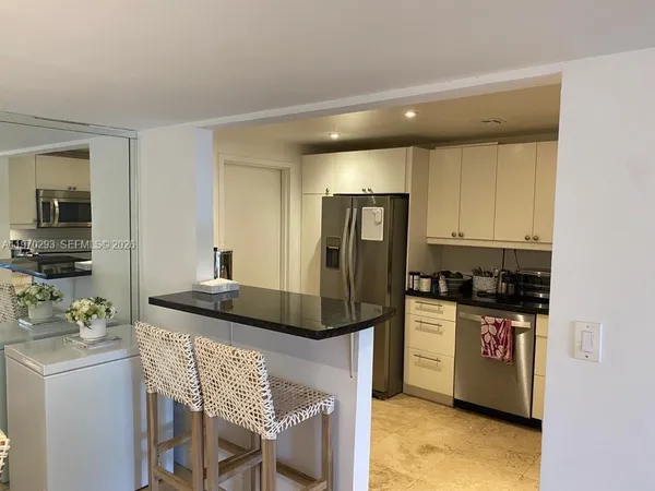 a kitchen with granite countertop a refrigerator and a stove top oven