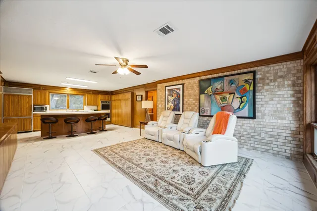 a living room with furniture a flat screen tv and floor to ceiling window