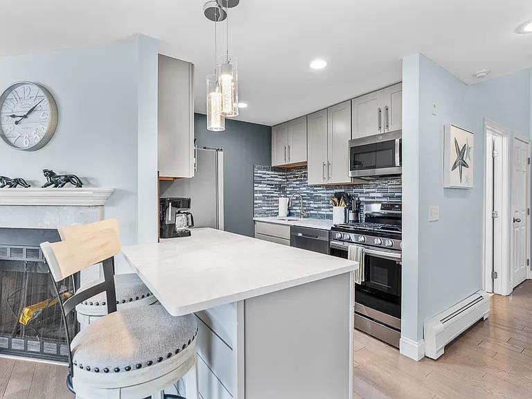 15 Riverview Avenue, Unit D Mashpee, MA 02649 - Photo 9 of 33 a kitchen with stainless steel appliances a stove a refrigerator and a dining table