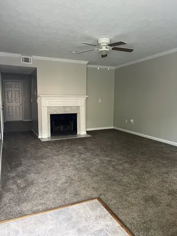 an empty room with a fireplace and chandelier fan