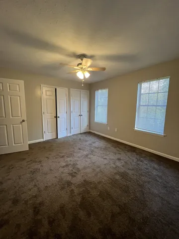 an empty room with windows and fan