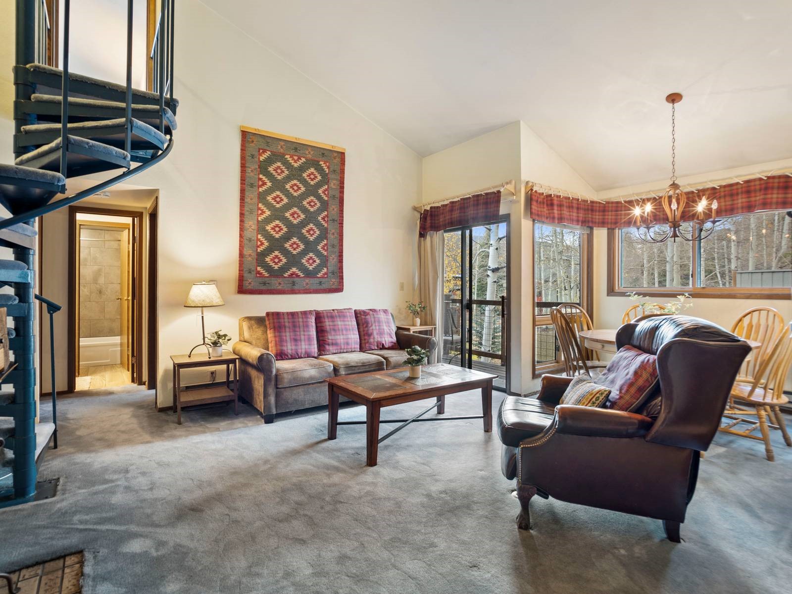 Living room featuring high vaulted ceiling, carpet flooring, and an inviting chandelier