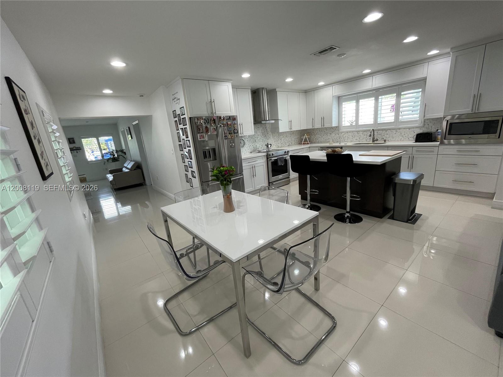 4161 Southwest 102nd Avenue Miami, FL 33165 - Photo 13 of 33 a kitchen with stainless steel appliances kitchen island granite countertop a refrigerator a stove a sink a dining table and chairs