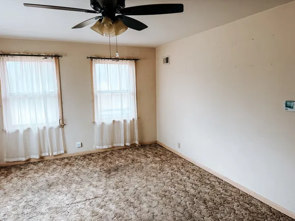 an empty room with windows and fan