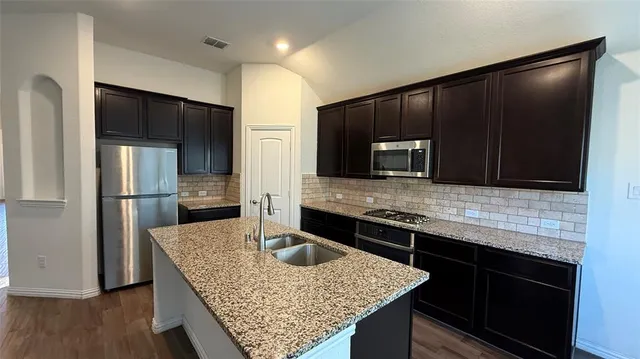 a kitchen with granite countertop a sink stove and refrigerator