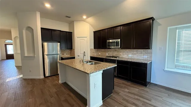 a kitchen with stainless steel appliances wooden cabinets a refrigerator and a stove top oven