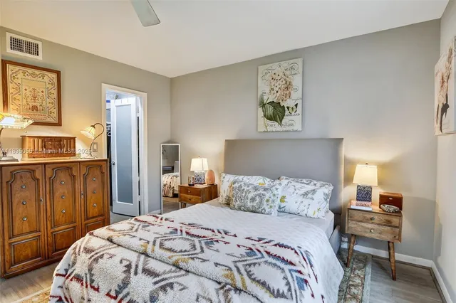 a bedroom with a bed a dresser and wooden floor