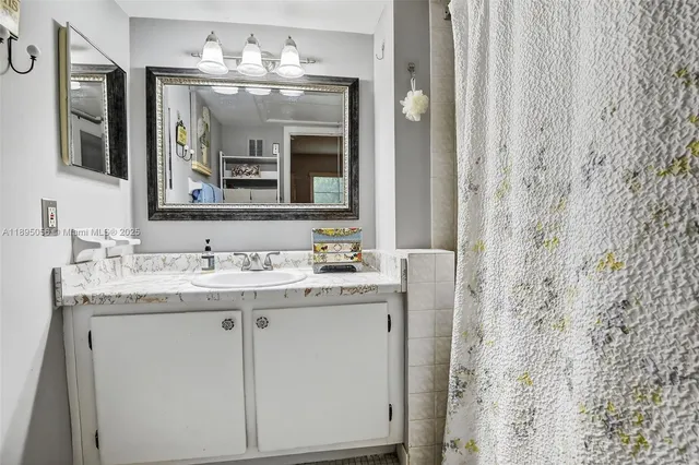 a bathroom with a granite countertop sink a large mirror and a shower