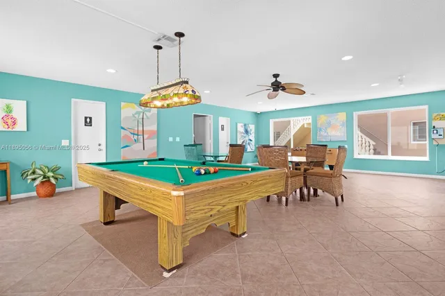 a room with chairs pool table and windows