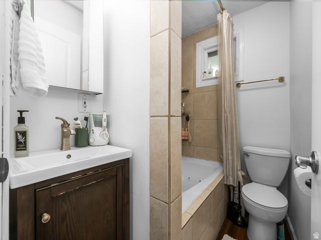 225 South 300 East Provo, UT 84606 - Photo 7 of 30 Bathroom featuring a single vanity with a dark wood-finish cabinet and integrated sink, a bronze-finish faucet, a mirrored medicine cabinet, a tiled shower/tub combination with a window, and a white toilet