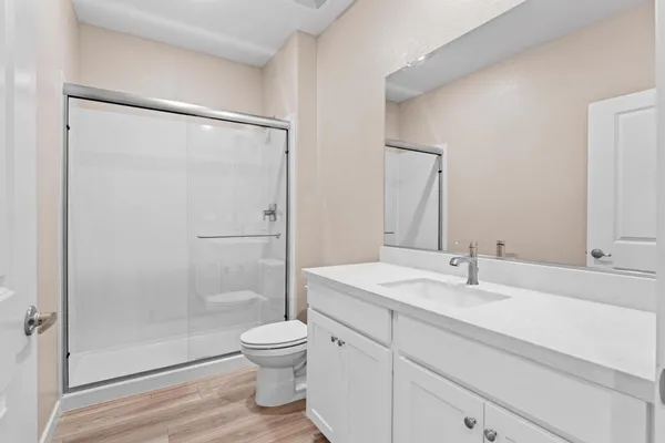 a bathroom with a shower sink vanity mirror and toilet