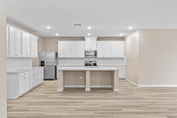 a large white kitchen with wooden floor and a sink