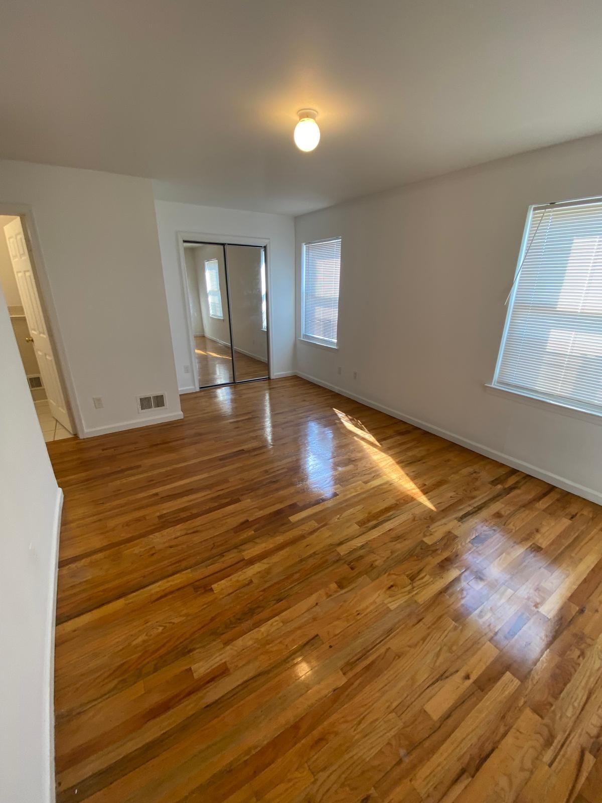 225 Belvidere Avenue, Unit 2 Jersey City, NJ 07306 - Photo 10 of 18 an empty room with wooden floor and windows