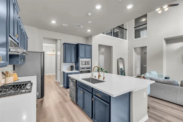 a kitchen with stainless steel appliances a dining table chairs refrigerator and cabinets