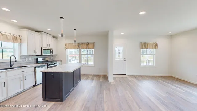 a kitchen with stainless steel appliances granite countertop a refrigerator a sink and white cabinets