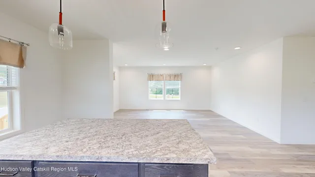 a large kitchen with stainless steel appliances kitchen island granite countertop a refrigerator a sink dishwasher and white cabinets with wooden floor