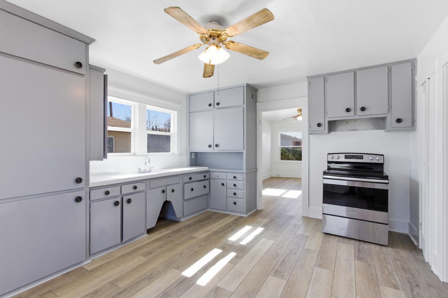 1014 3rd Street Los Banos, CA 93635 - Photo 7 of 21 a large white kitchen with cabinets a sink and stainless steel appliances