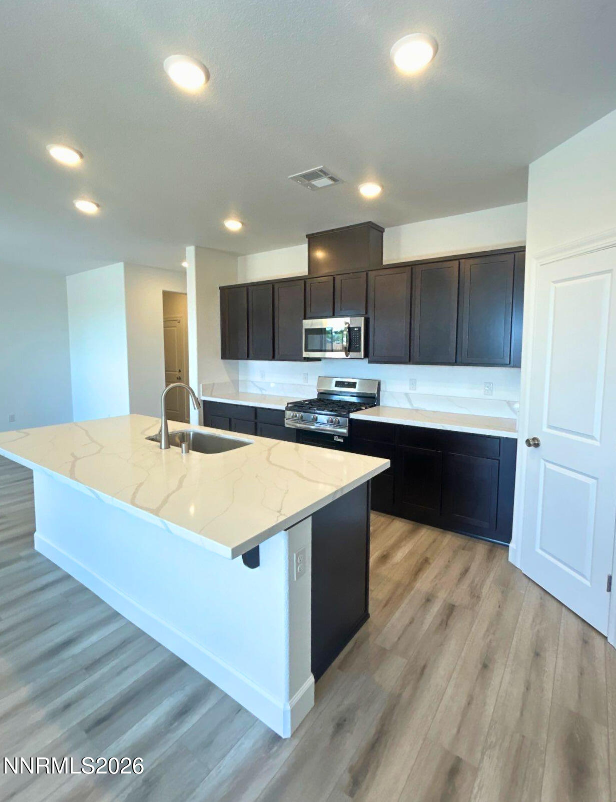 3453 Payton Way Fernley, NV 89408 - Photo 3 of 15 a large kitchen with kitchen island a sink dishwasher a stove and a refrigerator with wooden floor