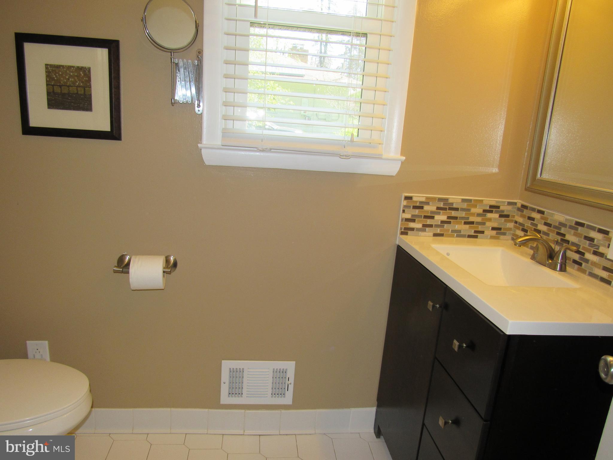 8710 Windsor Mill Road Baltimore, MD 21244 - Photo 15 of 30 a bathroom with a sink a toilet and a window