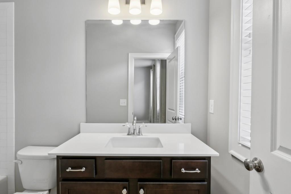 3899 Glenview Club Lane Duluth, GA 30097 - Photo 29 of 38 a bathroom with a sink a toilet and a mirror