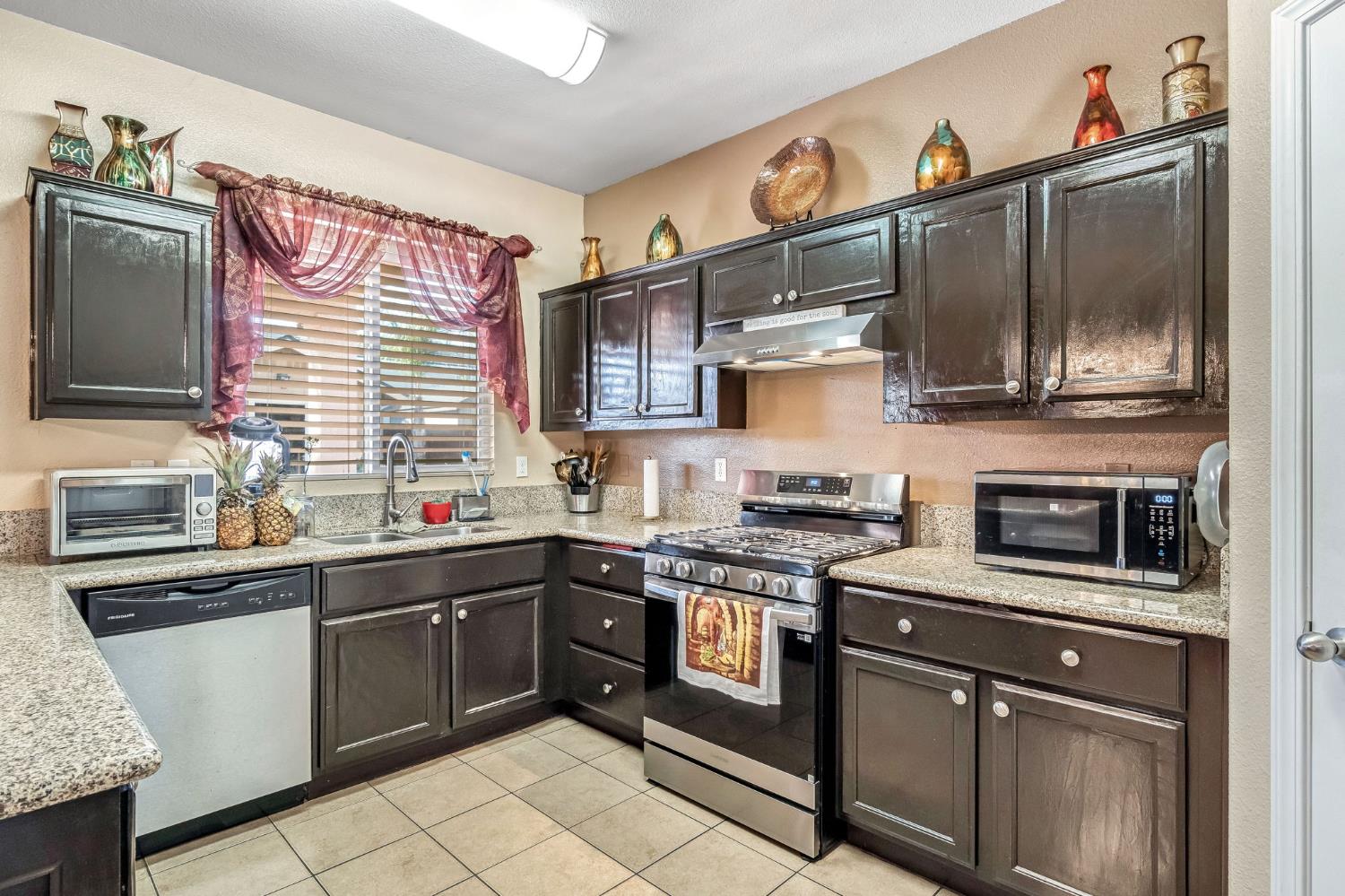 877 Sandra Avenue Sanger, CA 93657 - Photo 13 of 40 a kitchen with stainless steel appliances granite countertop a sink stove and microwave