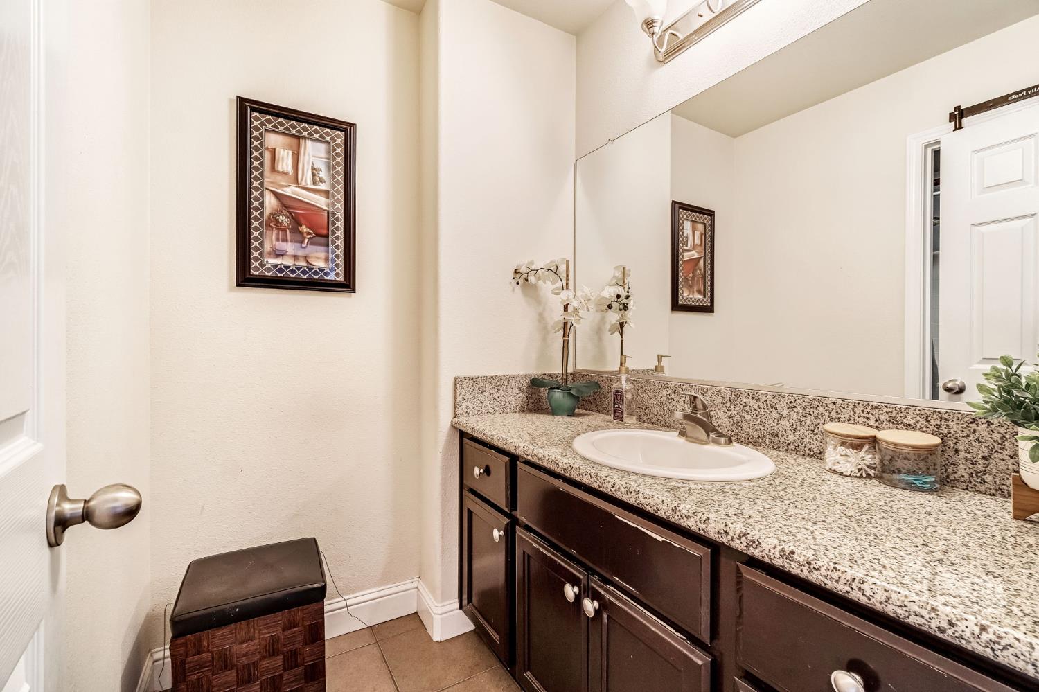 877 Sandra Avenue Sanger, CA 93657 - Photo 22 of 40 a bathroom with a granite countertop sink a toilet and mirror