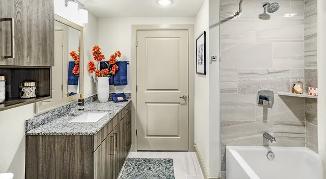 a bathroom with a granite countertop tub sink and mirror