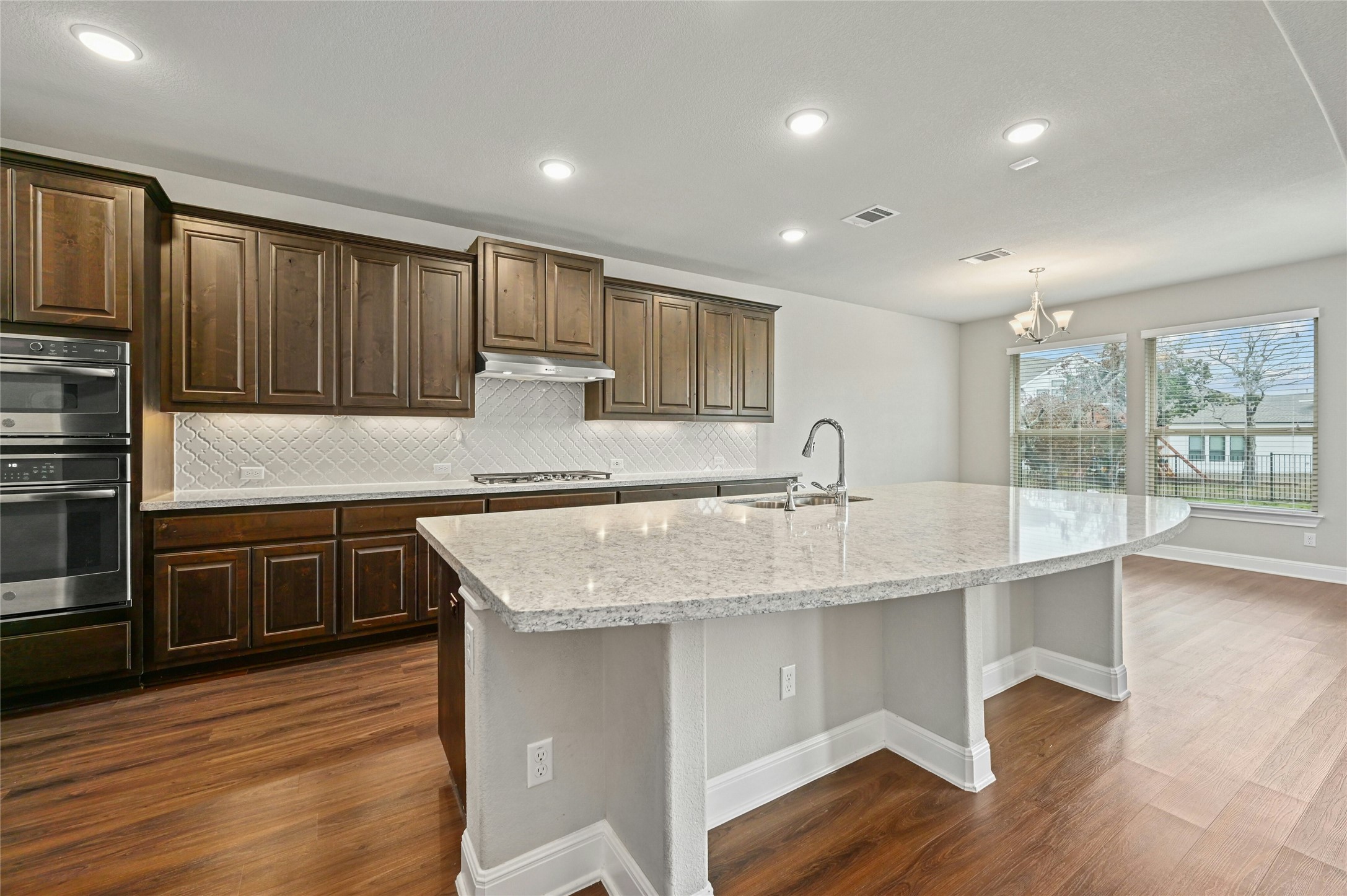 4124 Florentine Road Leander, TX 78641 - Photo 12 of 37 Kitchen with sink, dark hardwood / wood-style floors, a kitchen island with sink, and an inviting chandelier
