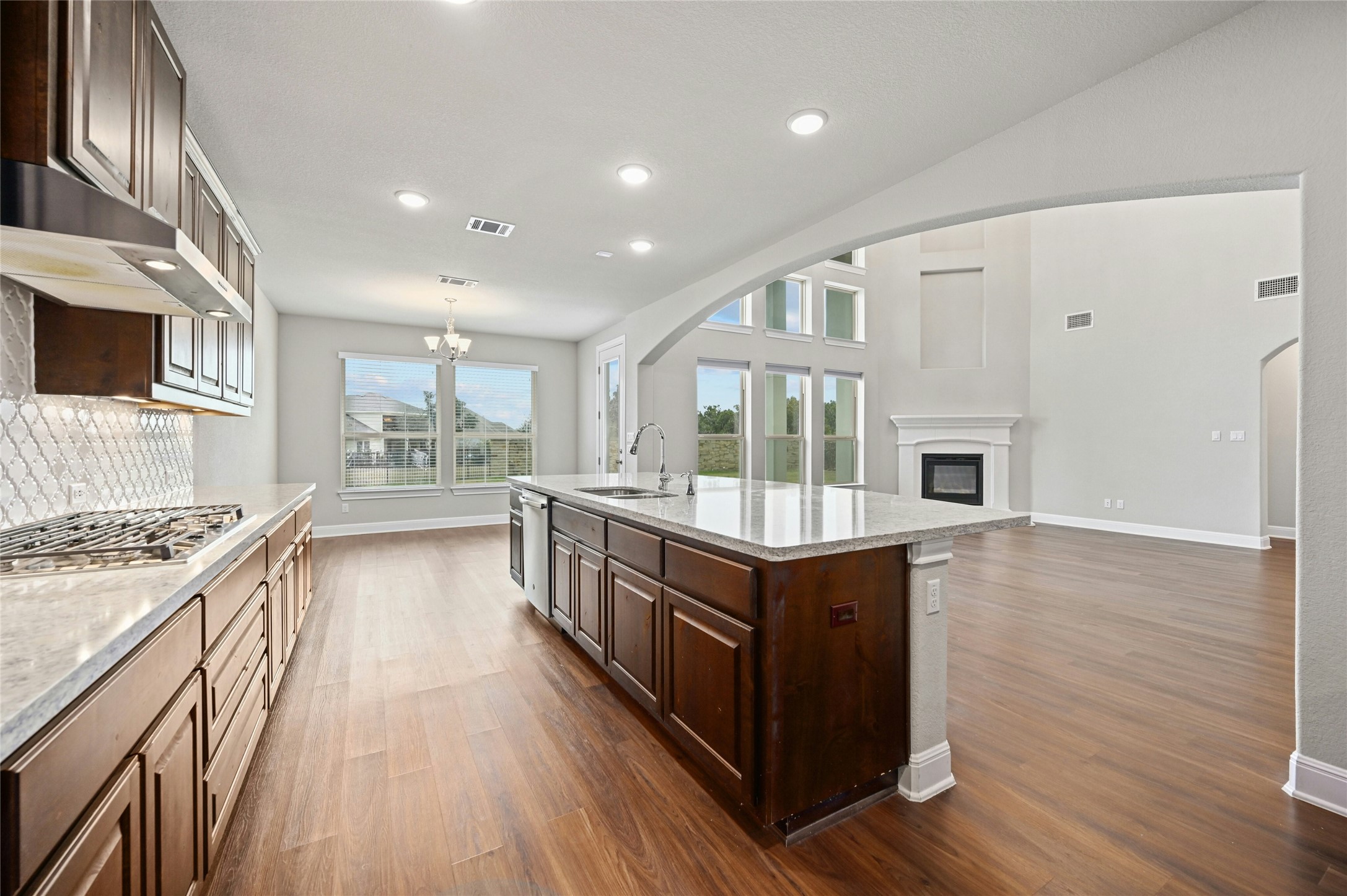 4124 Florentine Road Leander, TX 78641 - Photo 14 of 37 Kitchen featuring a center island with sink, decorative backsplash, stainless steel gas cooktop, light stone counters, and sink