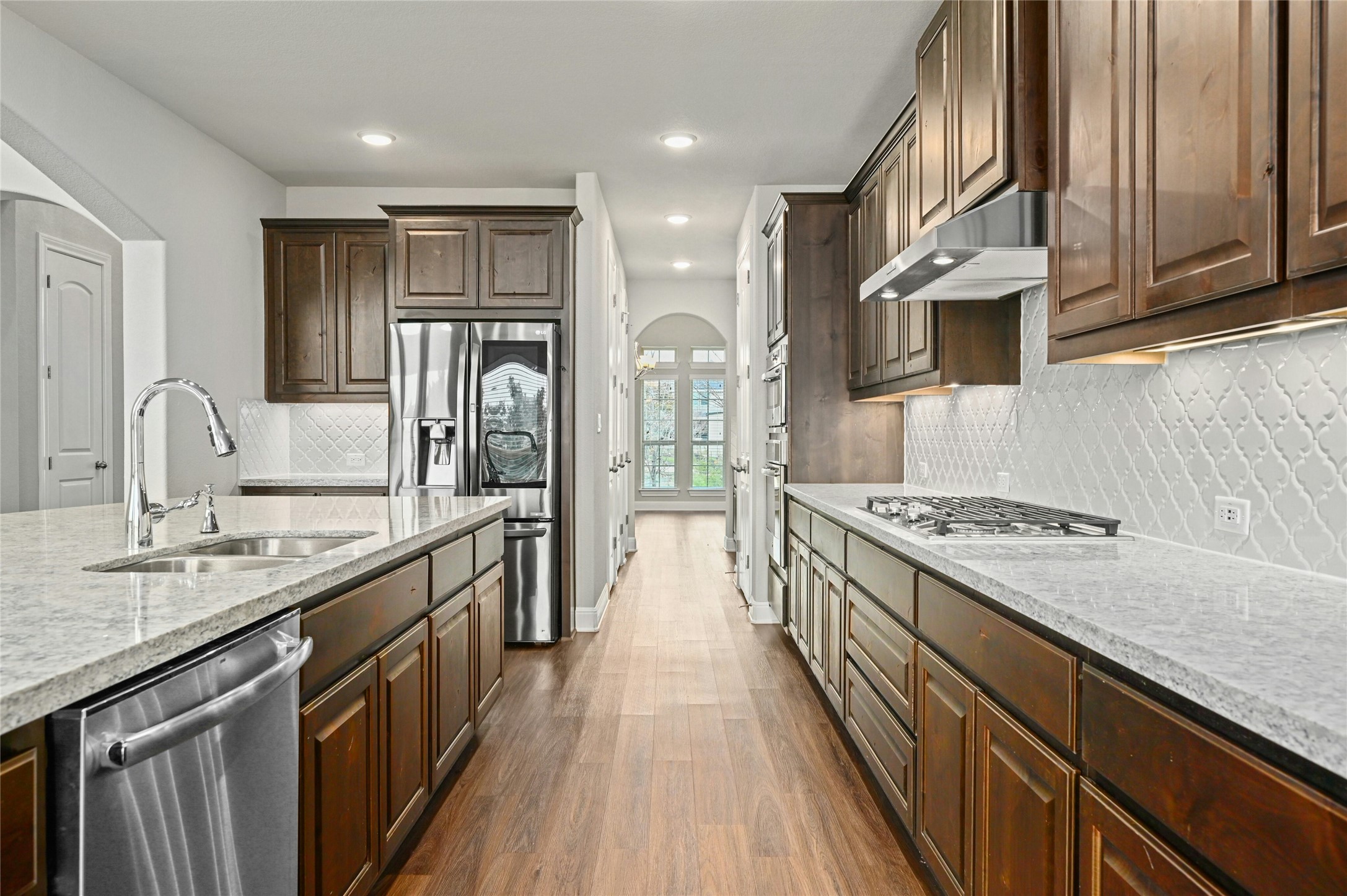 4124 Florentine Road Leander, TX 78641 - Photo 19 of 37 Kitchen featuring stainless steel appliances, dark wood-type flooring, light stone countertops, dark brown cabinetry, and sink