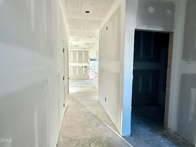 a view of a hallway with wooden floor and a bathroom