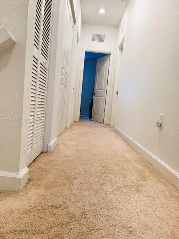 a view of a hallway with closet and bathroom