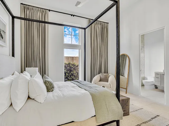 a large white bed sitting in a bedroom next to a large window