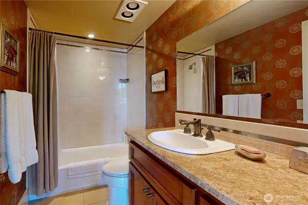 a bathroom with a granite countertop sink toilet and shower