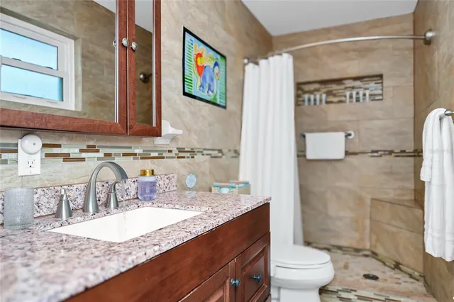a bathroom with a granite countertop sink a mirror a toilet and shower