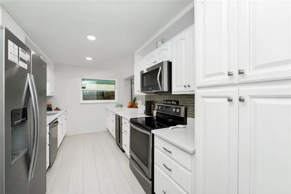 a kitchen with white cabinets and stainless steel appliances