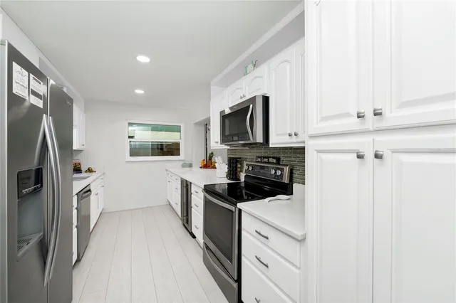 a kitchen with white cabinets and stainless steel appliances