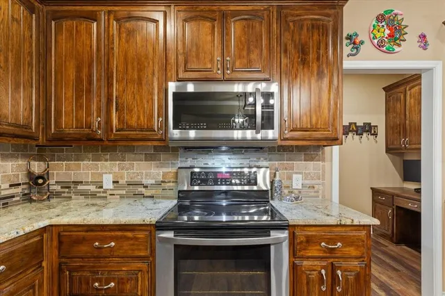 a kitchen with granite countertop a stove top oven microwave and cabinets