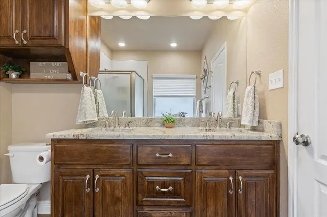 a bathroom with a granite countertop sink a toilet and a mirror