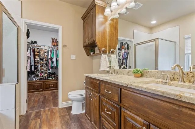 a bathroom with a granite countertop sink a toilet a mirror and shower