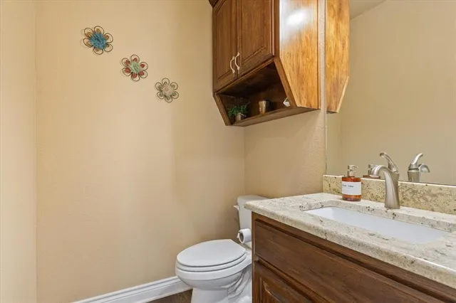 a bathroom with a granite countertop sink and a toilet