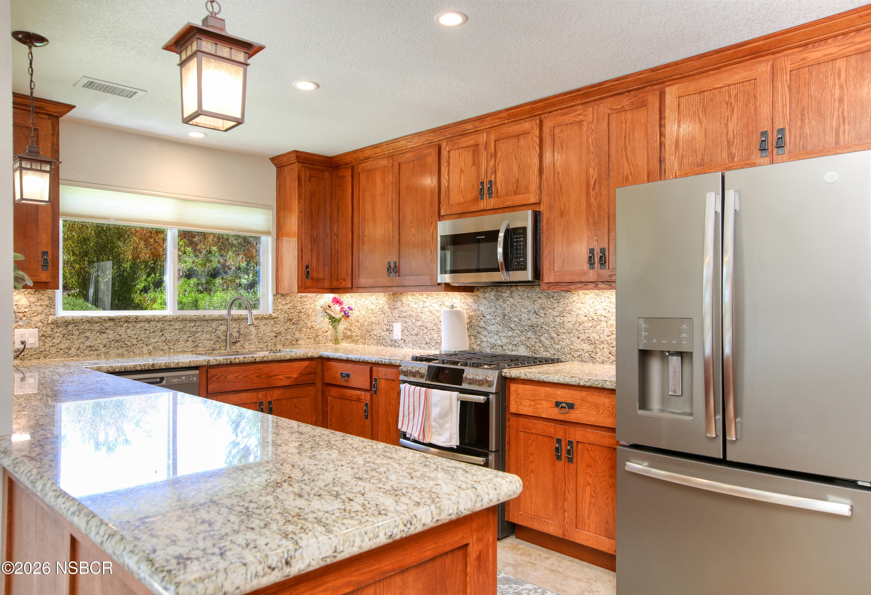 a kitchen with stainless steel appliances granite countertop a sink stove microwave and refrigerator