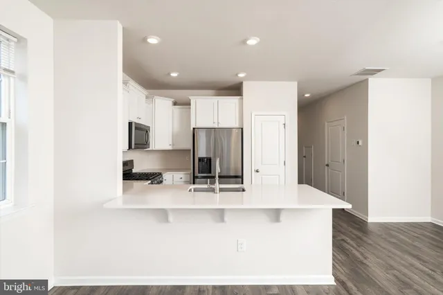 a large kitchen with stainless steel appliances a large counter top and a refrigerator